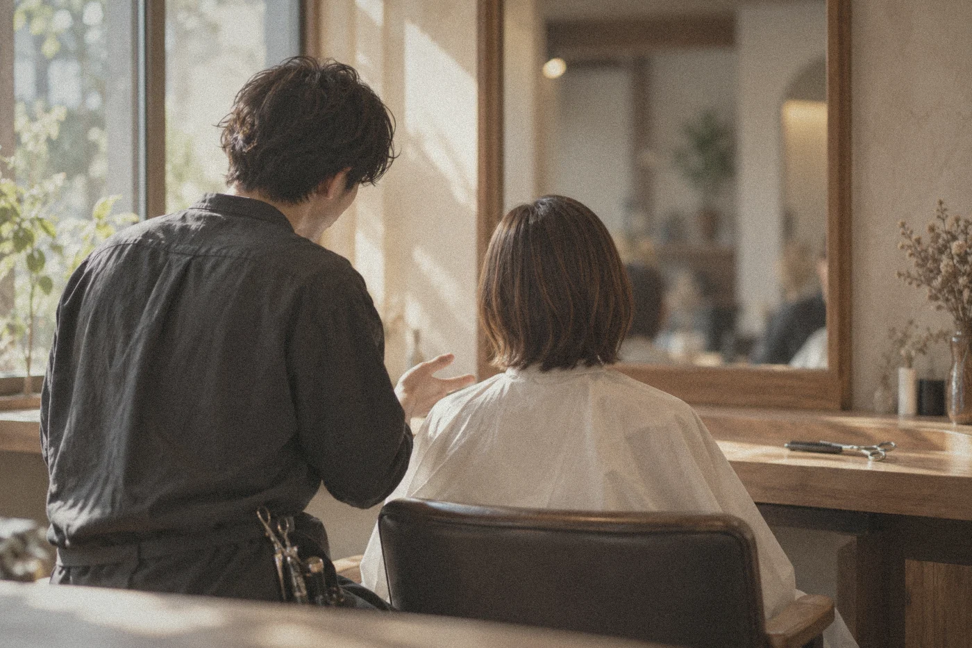 美容師さんが、席のお客様に話しかけている後ろ姿